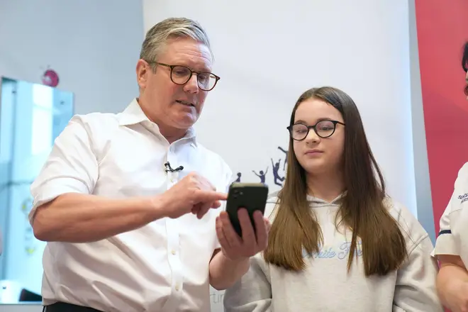 Labor leader Sir Keir Starmer meets Holly Burbidge, 12, as she looks at a smart phone that can help monitor sugar levels.